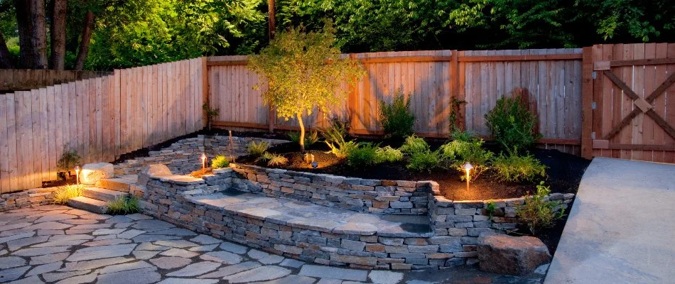 Landscape bed and retaining wall illuminated by lights in White Plains, NY.