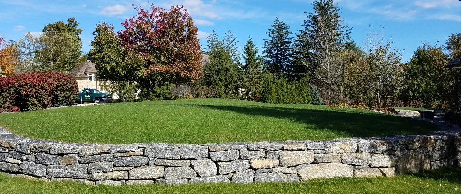 Retaining wall in Greenwich, CT, with green grass and trees.