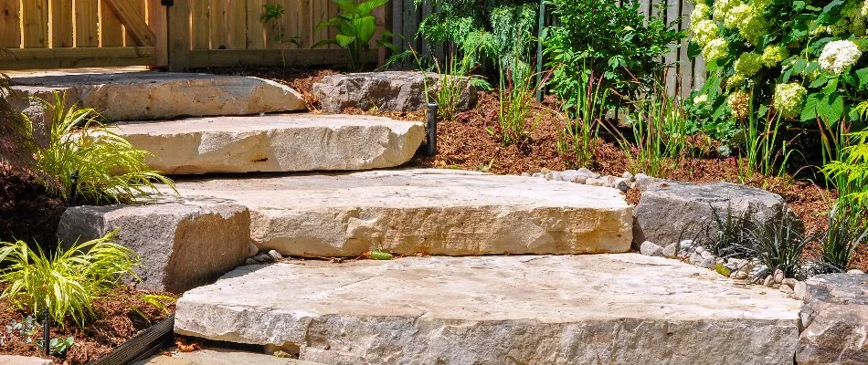 Stone outdoor steps leading up to a fence.